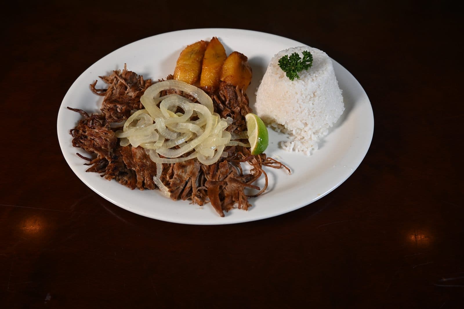 Ropa Vieja — shredded flank steak in creole sauce with rice and plantains