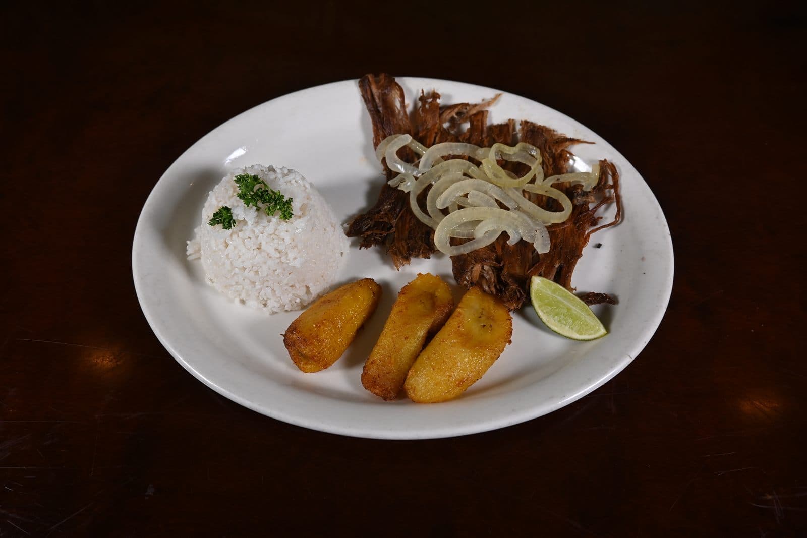 Palomilla Steak topped with sautéed onions, rice and sweet plantains