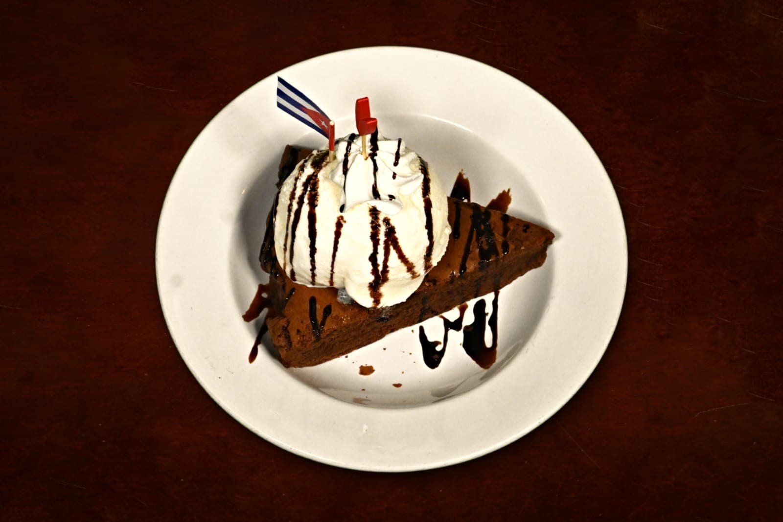 Brownie Sundae: brownie, ice cream & chocolate drizzle, plated on a dark wood table