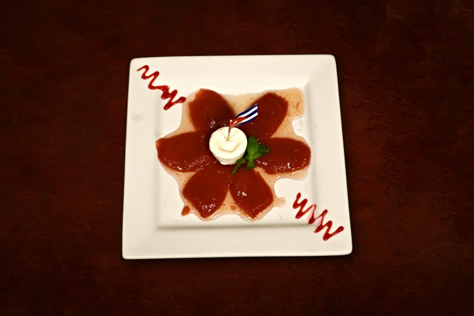Cascos de Guayaba: sweet guava with quesito crema, plated on a dark wood table