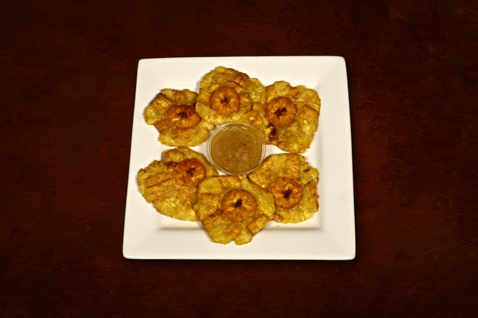 Tostones: fried green plantains, a Cuban staple, plated on a dark wood table