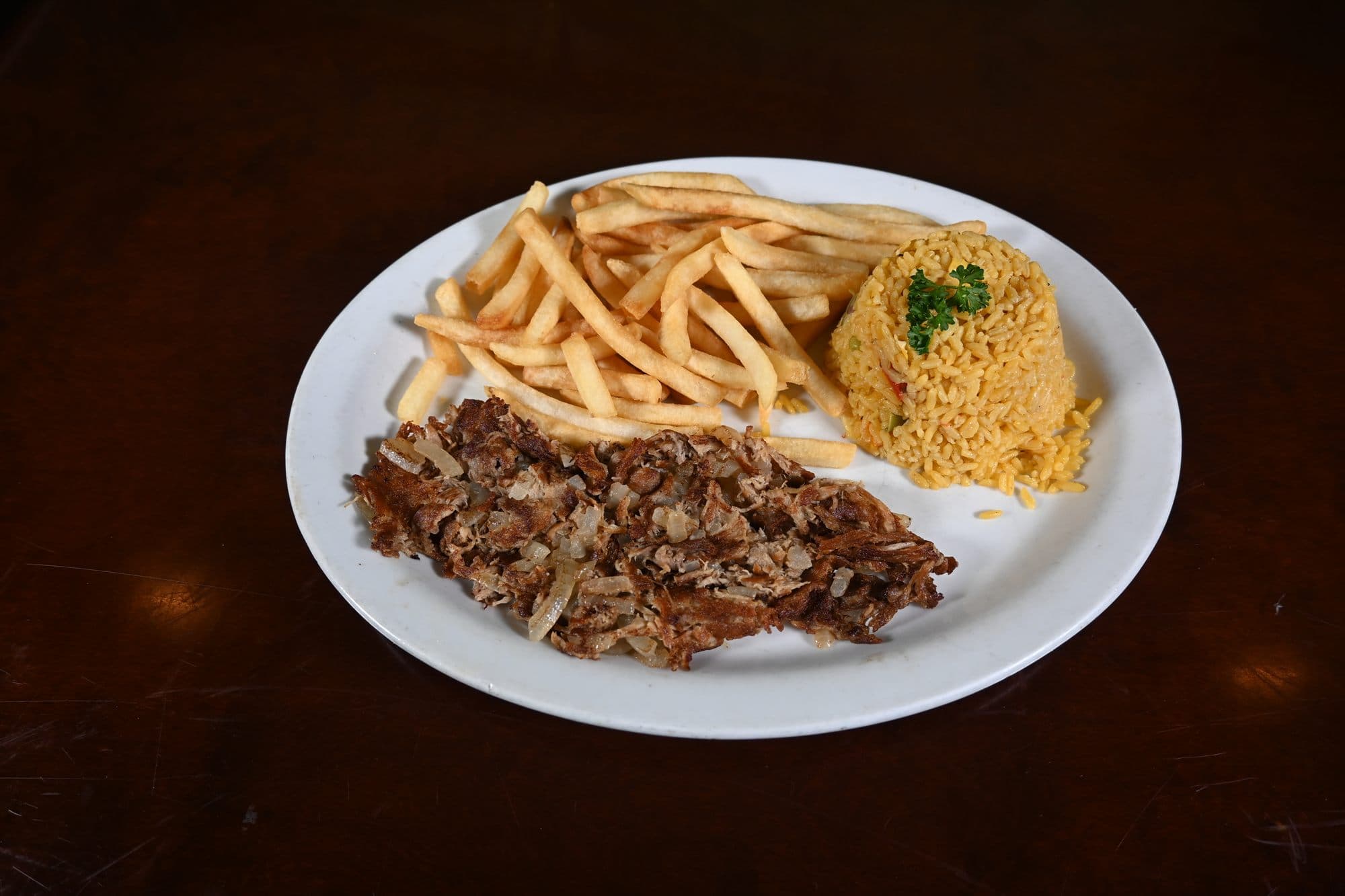 Lechón Asado — crisped roast pork with sautéed onions, yellow rice and fries